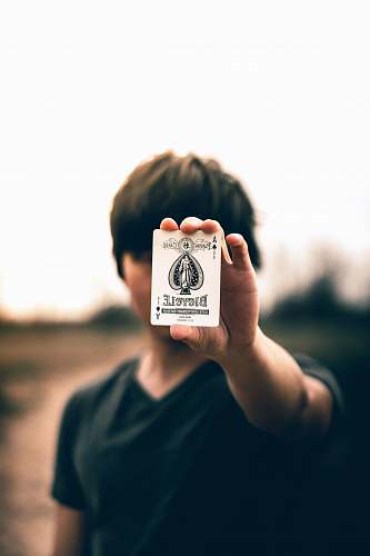 person selective focus photography of person holding ace of spades card human