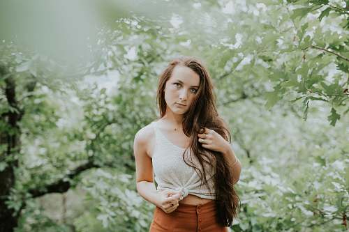 person selective focus photography of woman in tank top standing in forest human