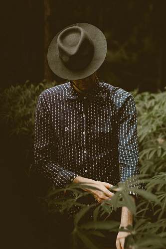 person shallow focus photography of man standing while folding his sleeve hat