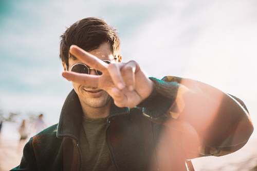 person shallow focus photography of smiling man doing peace sign human