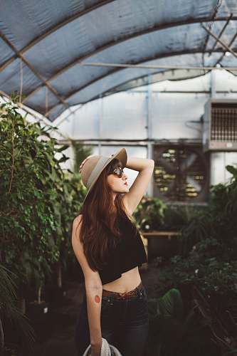 sunglasses shallow focus photography of woman posing while holding her hat at the garden plant