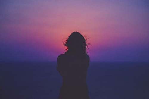 person silhouette of a woman with pink and purple sky silhouette