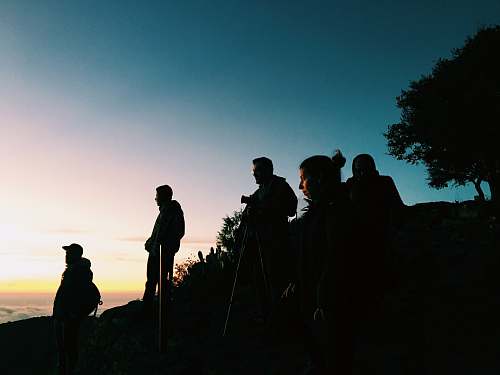 human silhouette of group of people standing on hill silhouette