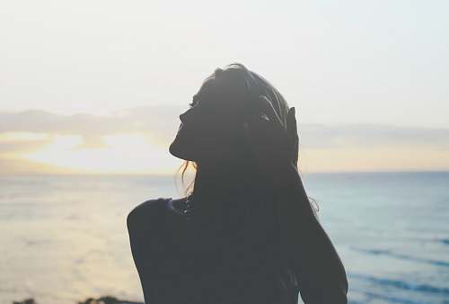 sky silhouette of woman across sea photo beach