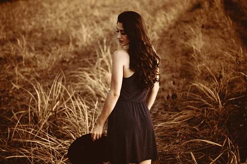 woman standing woman holding hat at the field during day grass