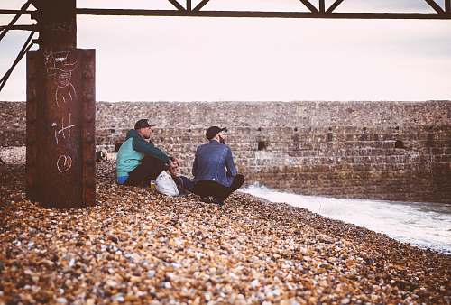 man two men sitting near body of water male