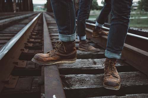 boot two people wearing brown shoes standing in train rail boots