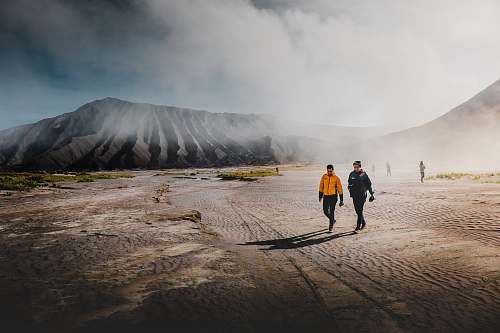 human two person standing on brown sands walking