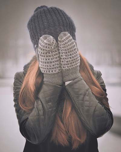 person woman covering her face mittens
