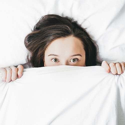 person woman covering her face with blanket sleep