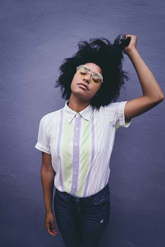 hair woman holding her hair near white concrete wall afro hairstyle