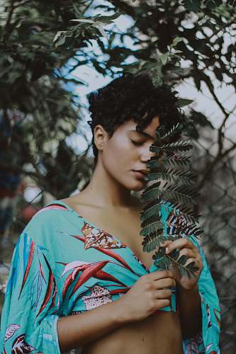 person woman holding leaf beside tree woman