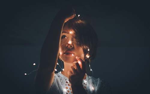 person woman holding light string in a dark room woman