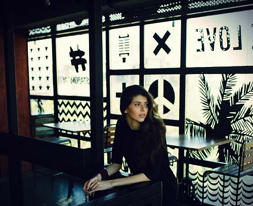 woman woman in black quarter-sleeved top leaning on black desk cafe