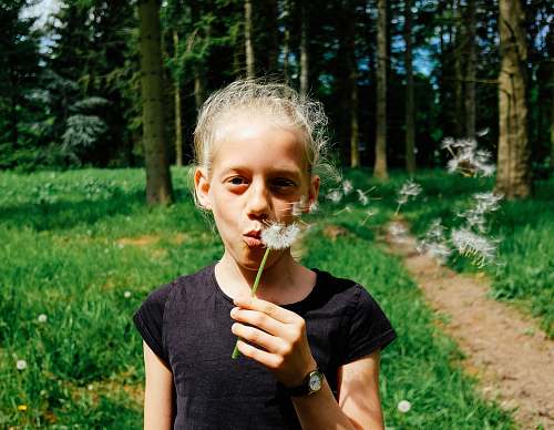 person woman in black shirt blowing dandelion human