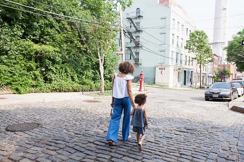 person woman in white cap-sleeved shirt and blue pants walking beside girl in gray tank top human