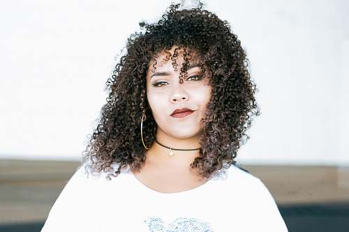person woman in white scoop-neck top in front of white wall hair