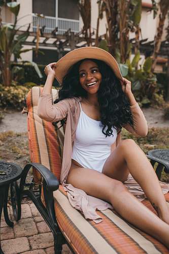 human woman in white swimsuit sitting on outdoor lounge smiling woman