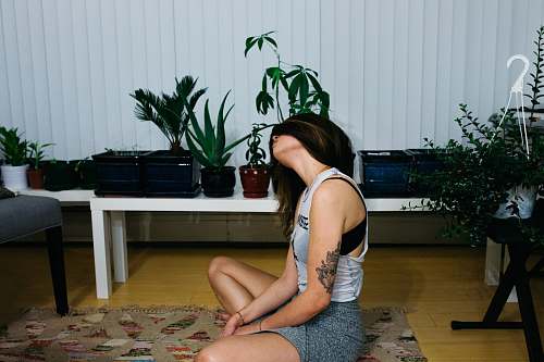 person woman sitting on area rug near table plant