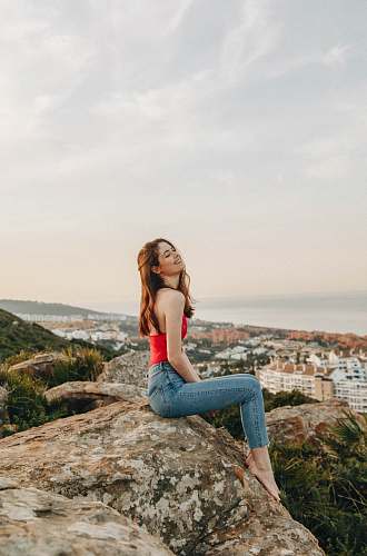 human woman sitting on rock during daytime woman