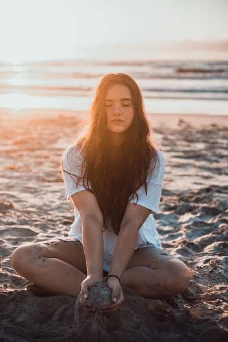 person woman sitting on sand holding sands during daytime human