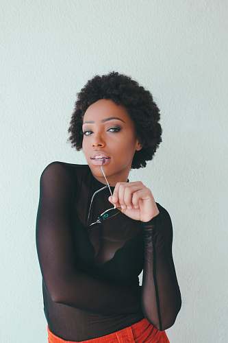 hair woman wearing crew-neck long-sleeved shirt holding sunglasses standing near wall human