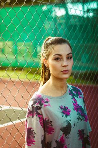 woman woman wearing floral top beside chain link fence during day female