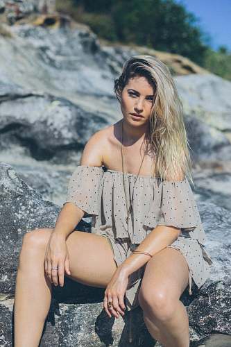 woman woman wearing gray and black polka-dotted cold-shoulder rompers while sitting on stone female