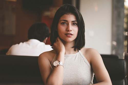 person woman wearing gray spaghetti strap shirt sitting on black leather sofa close-up photo human