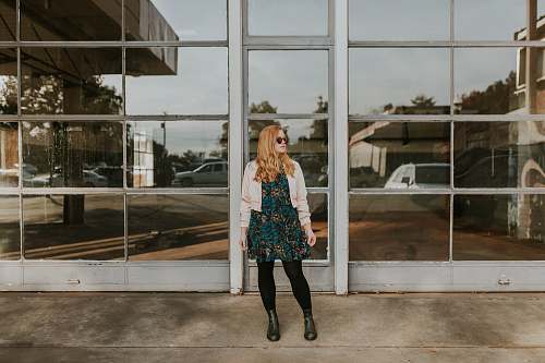 person woman wearing pink bolero and black leggings standing in front of glass wall female