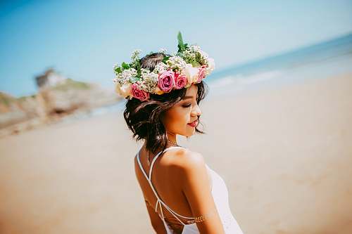person woman wearing white halter dress and floral tiara at shore during daytime human