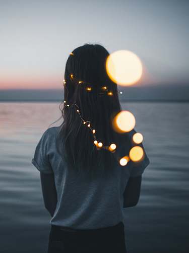 person woman wearing white shirt facing the ocean photo during golden hour human