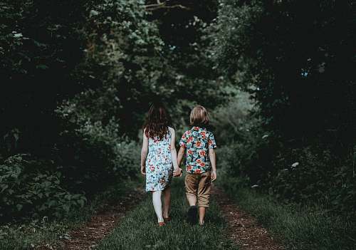 people boy and girl walking hand in hand towards the woods kid