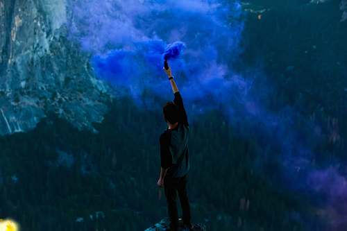 people man holding blue powder while raising hand smoke