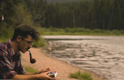 people man smoking on pipe beside lake human