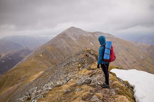 mountain person at peak of mountain carrying red backpack nature