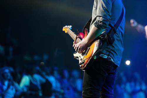 people selective focus photography of man playing electric guitar on stage music