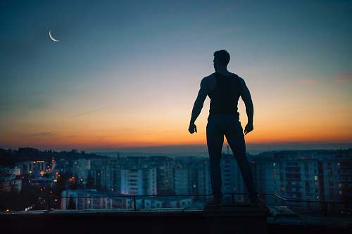 people silhouette photography standing on peak front of high-rise buildings silhouette