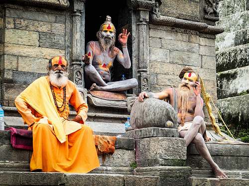 people three monks sitting on concrete temple during daytime human