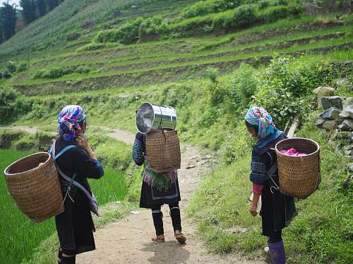 people three people wearing brown wicker baskets walking on road human