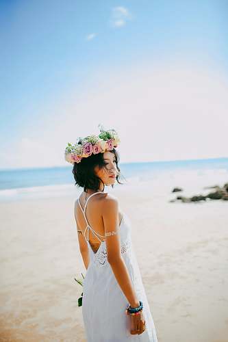 people woman wearing white spaghetti-strap dress standing on the seashore during daytime photography human