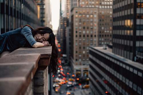 people woman leaning on top building rail during daytime building