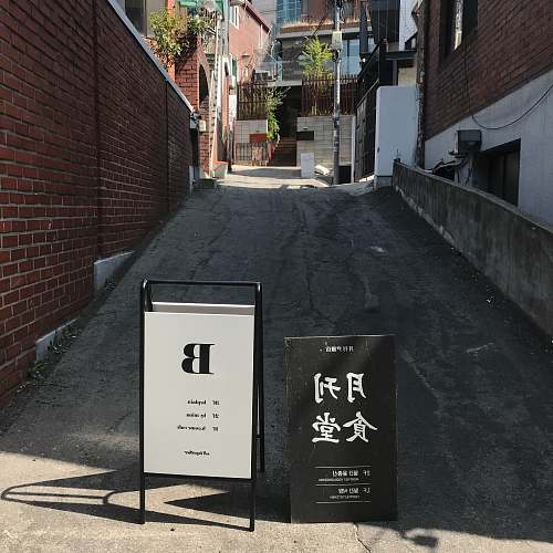 city black and white road signs between buildings road