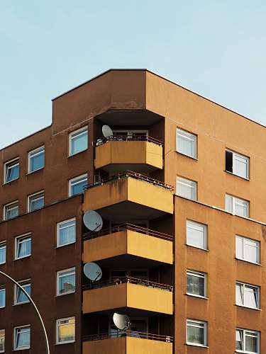 city brown building with parabollic antenna during daytime high rise