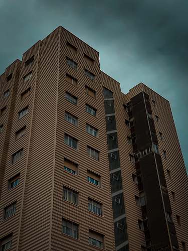 city brown buildings under gray clouds high rise