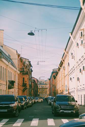 city different vehicles on road near building under blue and white skies during daytime road
