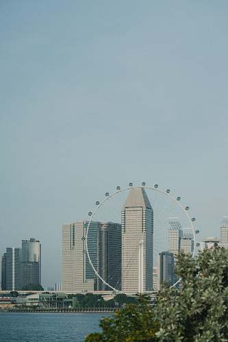 city ferries wheel near highrise building and sea urban