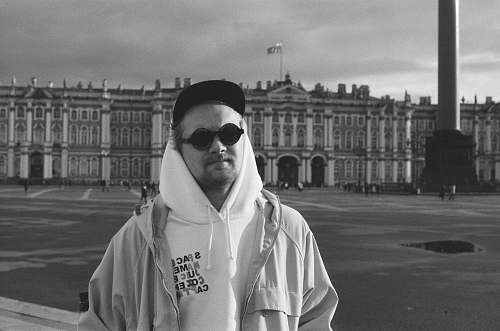 city grayscale photography of man standing near Hermitage Museum in Russia black-and-white