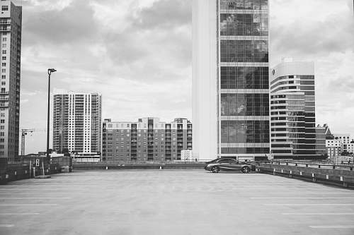 city grayscale photography of vehicle parking with high-rise building background black-and-white