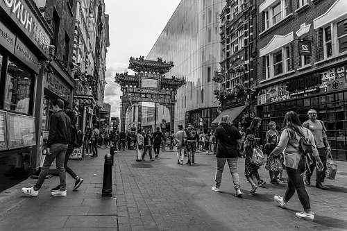 downtown greyscale photography of people walking on street between buildings black-and-white
